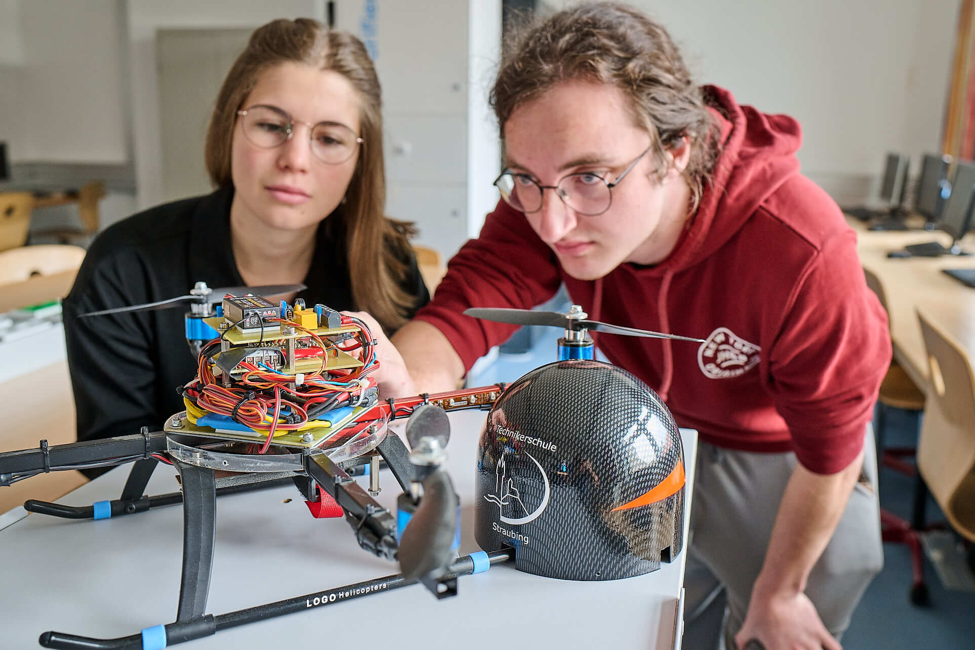 Zwei Schüler betrachten eine aufgeschraubte Drohne